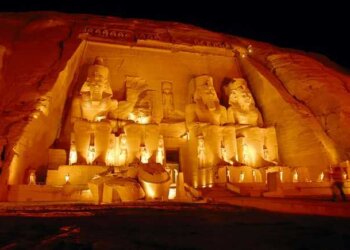 The Great Temple at Abu Simbel lit up at night, with four figures carved into the rock around the entrance