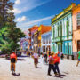 Line of colourful buildings with pedestrians walking on street