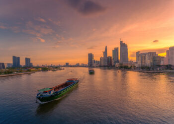 Aerial sunset view of Bitexco Tower, buildings, roads, Bason bridge and Saigon river in Ho Chi Minh city