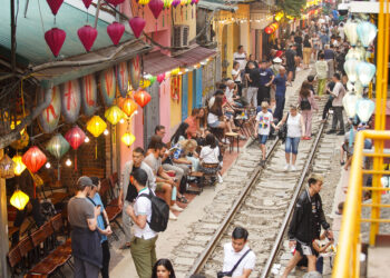 Hanoi train street as seen from above with tourists walking along or sitting by the train tracks