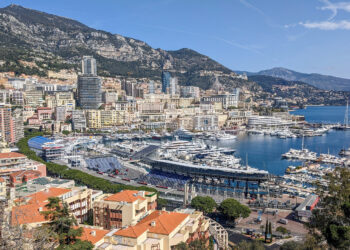 Panoramic view of Monaco cityscape with Port Hercule, luxury yachts, and mountains