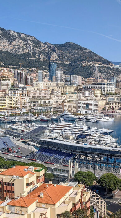 Panoramic view of Monaco cityscape with Port Hercule, luxury yachts, and mountains