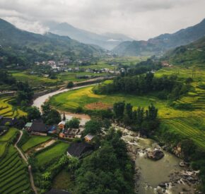 Wide angle aerial shot of Sapa mountains in Vietnam, a river flows along a valley with rice fields on both sides