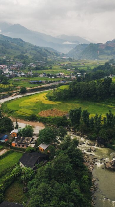 Wide angle aerial shot of Sapa mountains in Vietnam, a river flows along a valley with rice fields on both sides