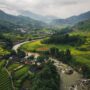 Wide angle aerial shot of Sapa mountains in Vietnam, a river flows along a valley with rice fields on both sides