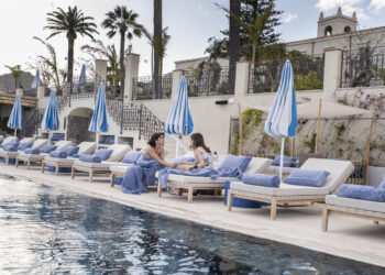 Simona Tabasco and Beatrice Granno on a set of deck chairs in front of the pool on set of The White Lotus season 2